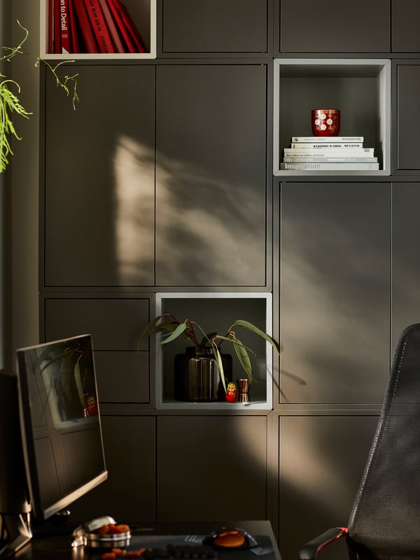 Combinaison de rangement EKET gris foncé couvrant un mur, près d’un bureau sur lequel est posé un écran.