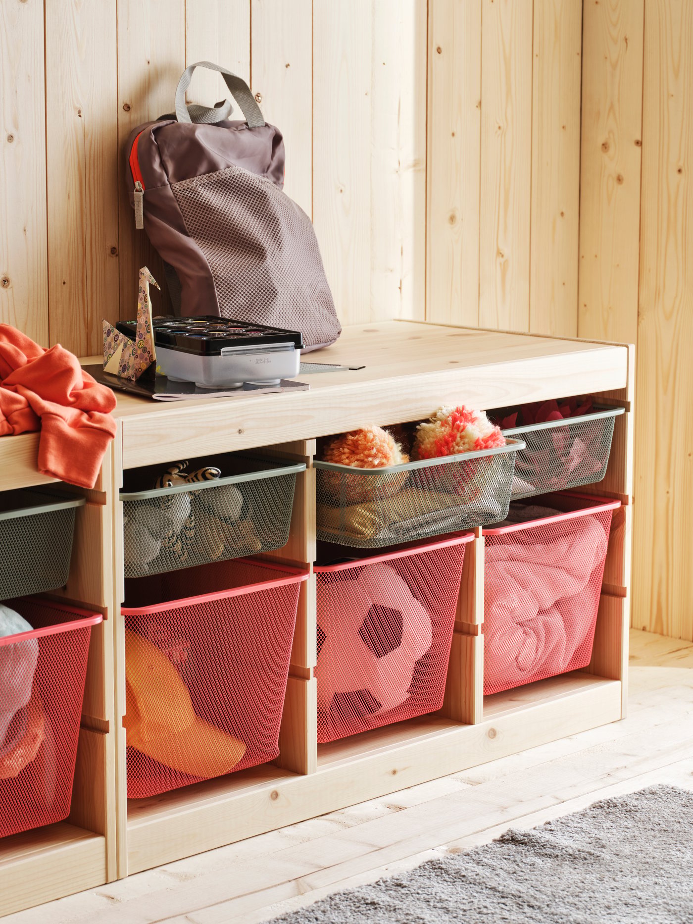 An IKEA TROFAST unit in birch with red and green wire baskets.