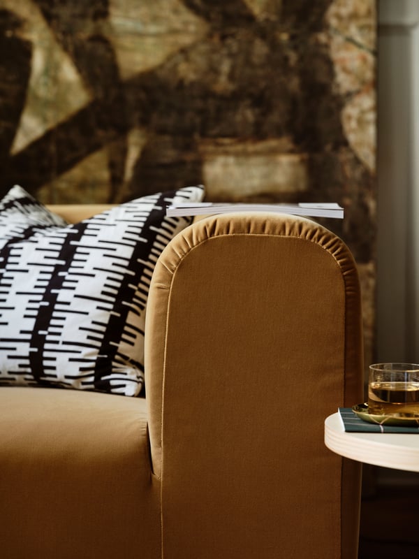 A cushion with a patterned black and white cushion cover rests in a beige STOCKHOLM 2025 two-seater sofa.