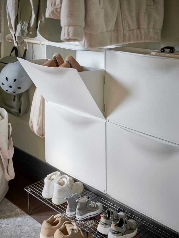 Two white TRONES shoe cabinets/storages with one door open showing shoes inside, plus a grey shoe rack below with more shoes.