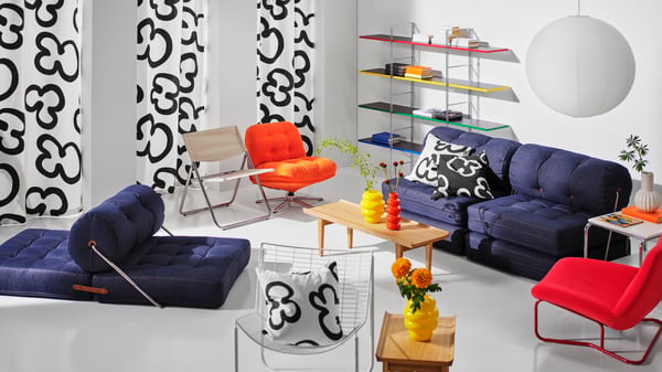 Several products from the Nytillverkad collection, like chairs, textiles and a shelving unit, are placed in a living room.
