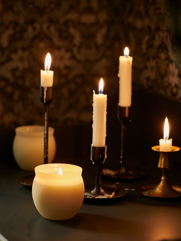 Un set de velas y un candelabro FULLTALIG con cuatro velas prendidas. Cada una consumida y con diferentes cantidades de esperma.