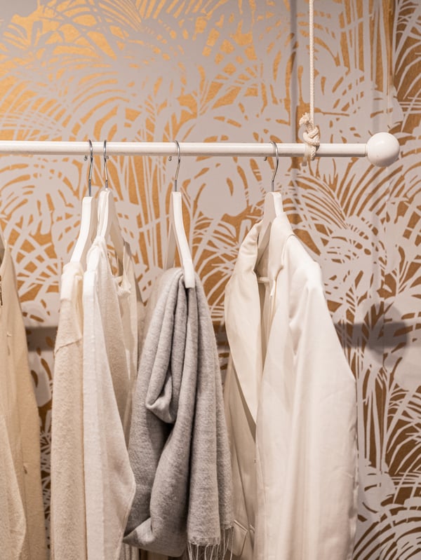 A clothing rack with three pieces of hanging clothing.