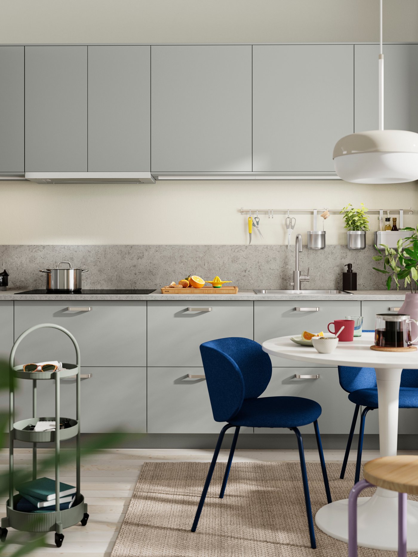 HAVSTORP kitchen fronts in light grey with black handles, a white tiled wall, and blue chairs around a table.