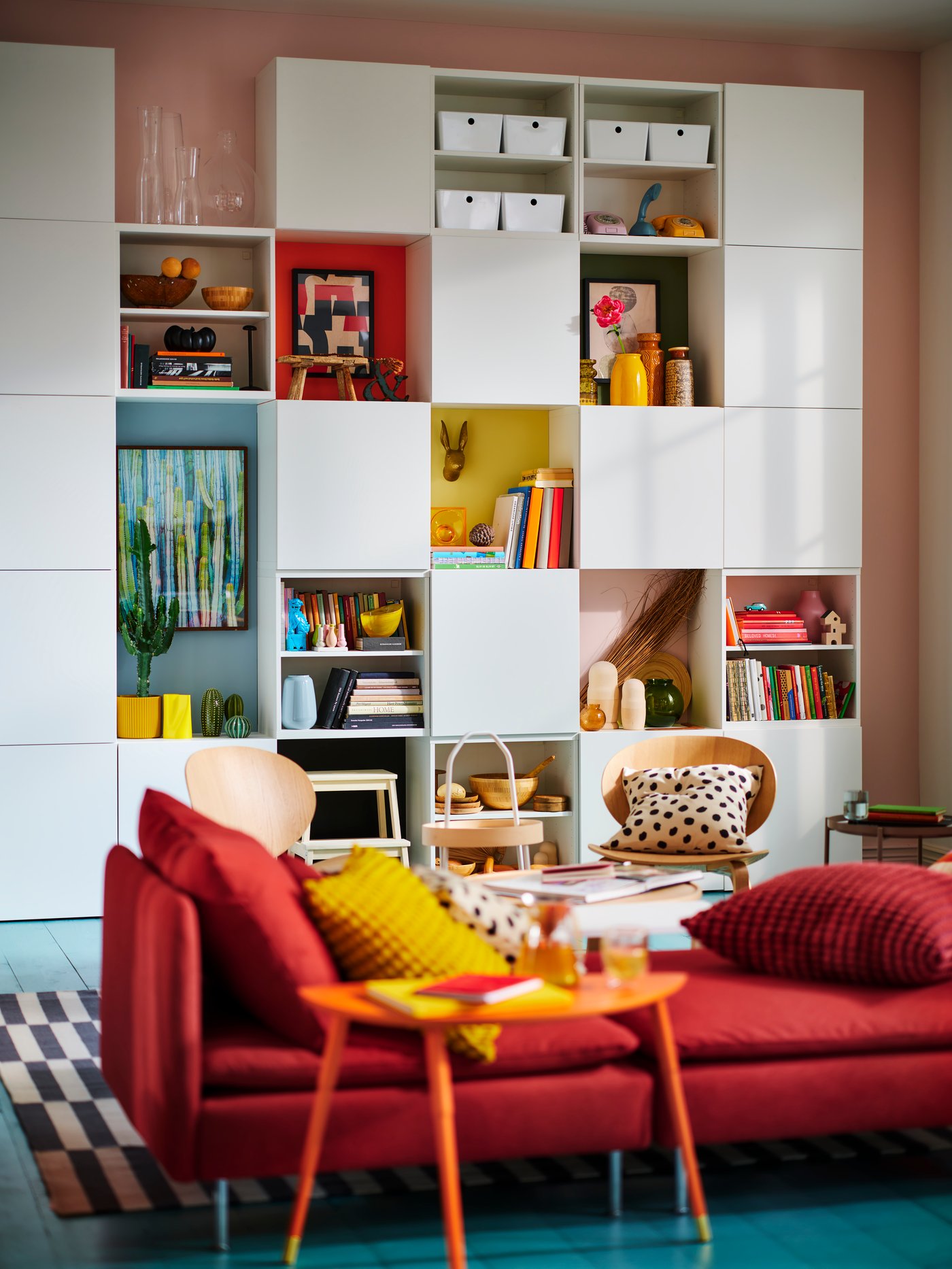 A large white BESTÅ wall unit sits on front of a red sofa
