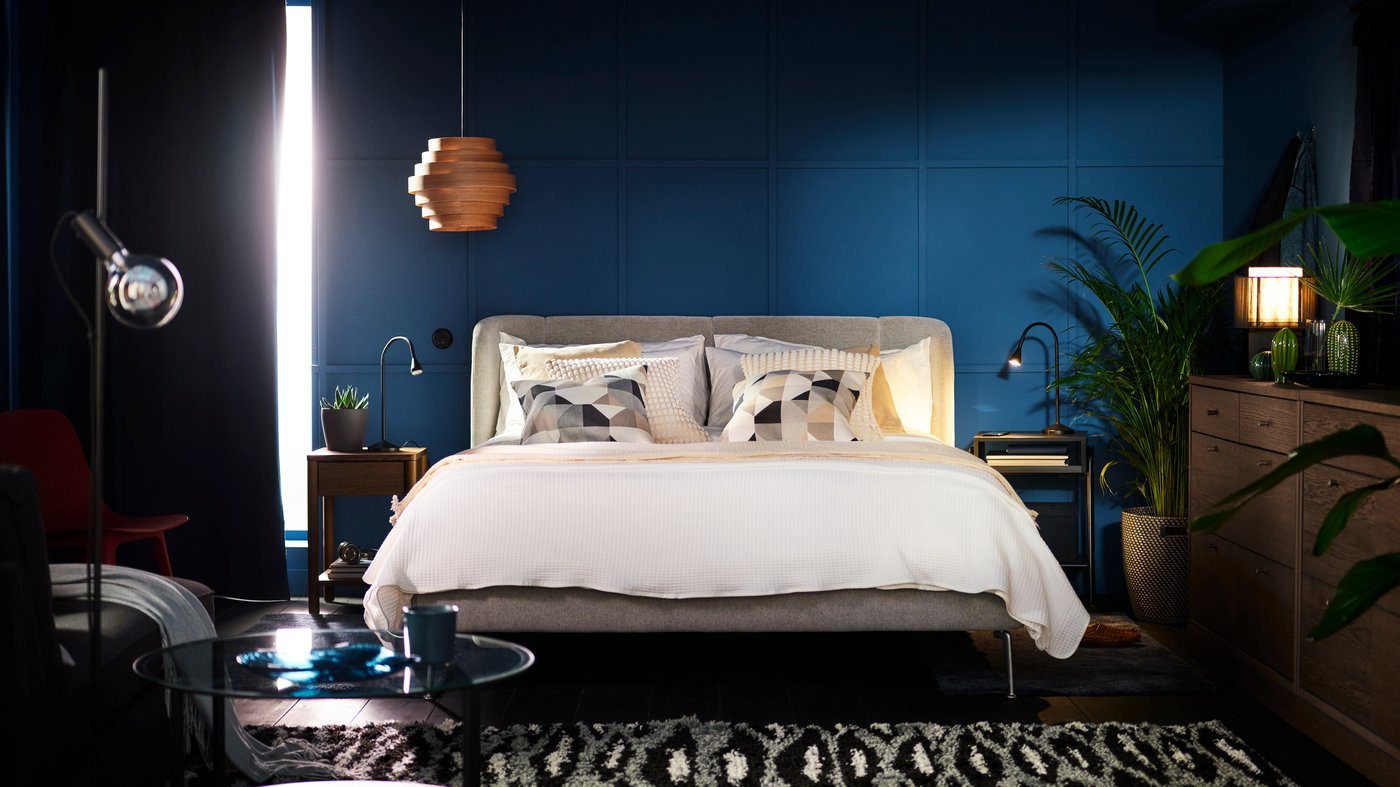 A TUFJORD upholstered double bed in a blue room covered in a white OFELIA VASS 3 duvet set and cushions in SANELA covers.
