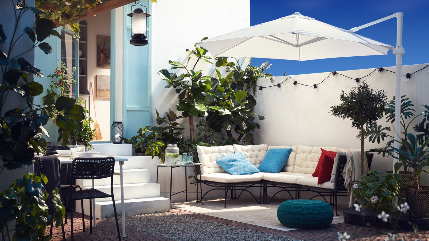 Terraza con sofás, mesa, sillas y plantas.