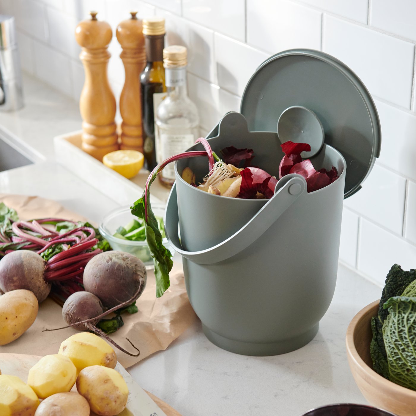 A grey-green FARMARKVAST bin with lid for organic waste in the kitchen