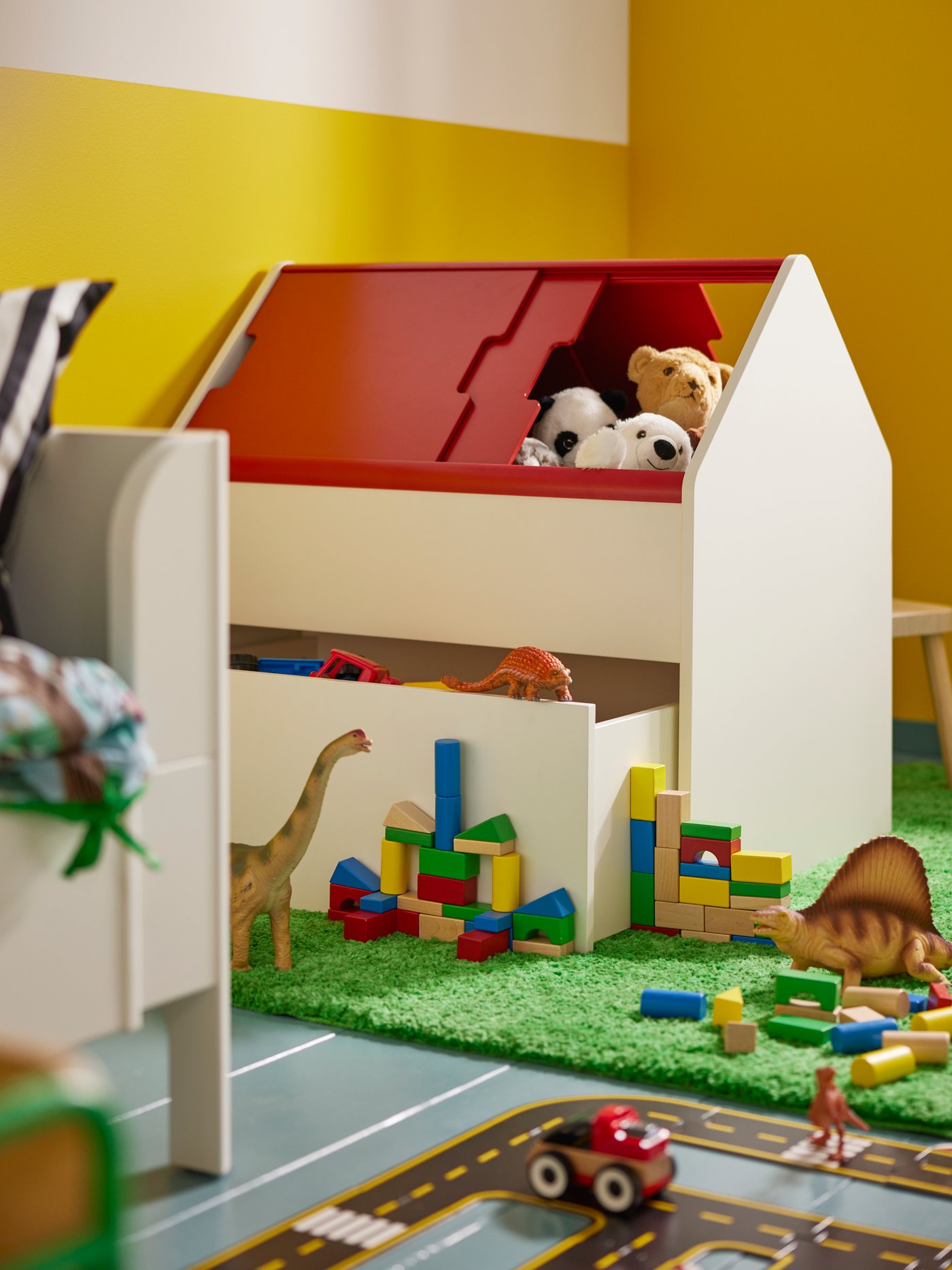 VITBJÖRN storage unit with drawer on top of bright green SKOSGDUVA rug and with toys scattered all around.