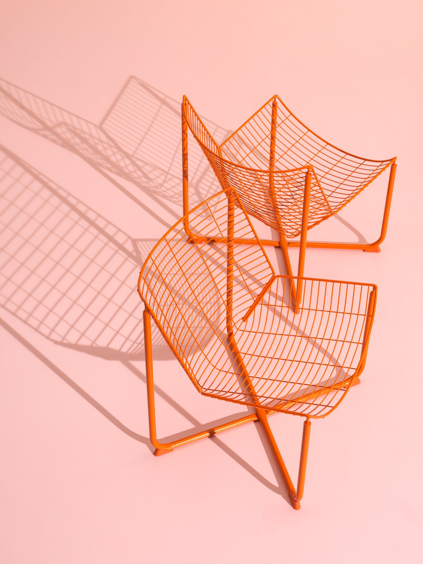 Two orange SKÅLBODA armchairs against a pink background.
