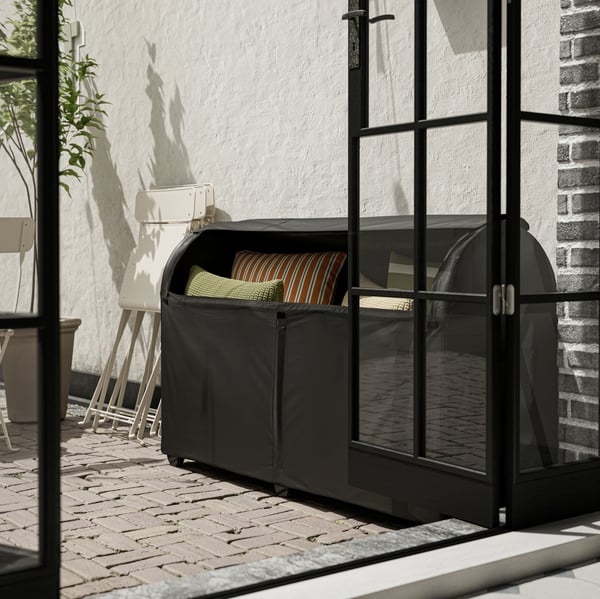 Eine schwarze TOSTERÖ Gartenmöbel-abdeckung ist um eine Gartenbox gewickelt.