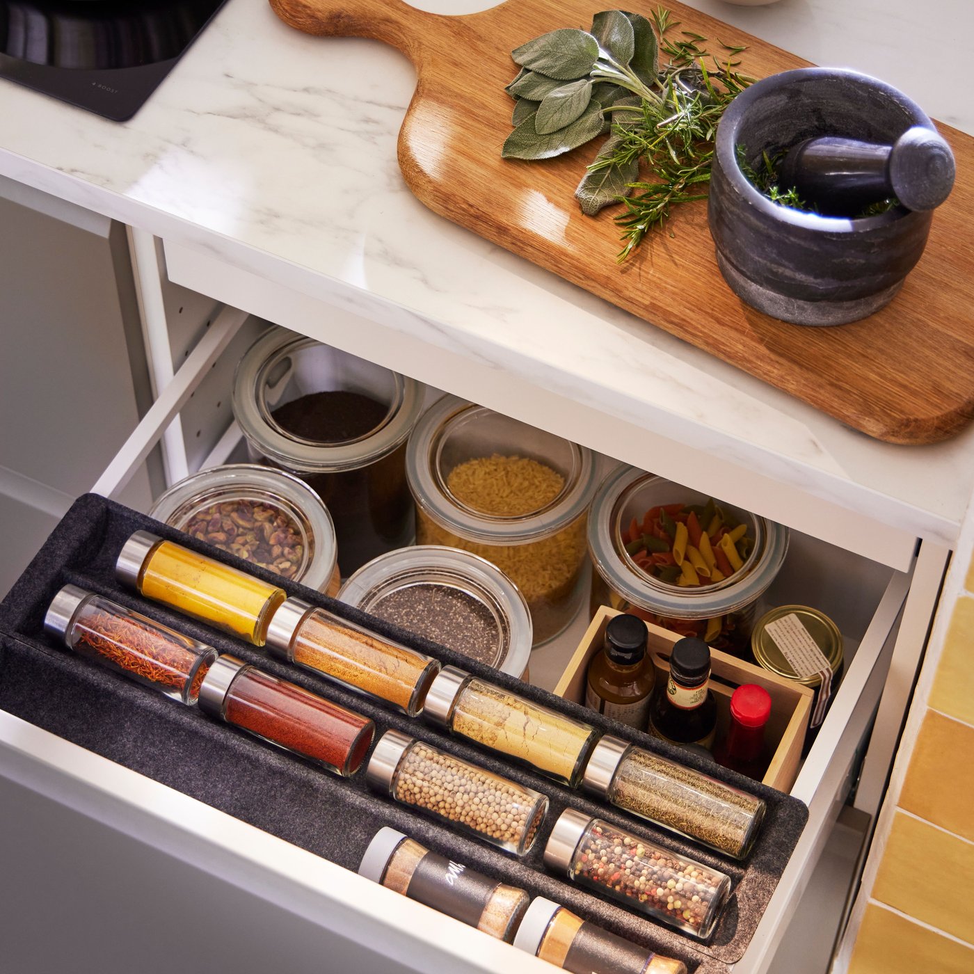 Kitchen drawer pulled open to reveal various IKEA 365+ food jars with dry condiments and spices inside, along with a spice rack hidden in the drawer.