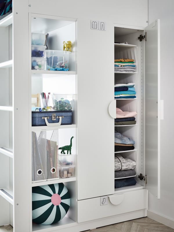 A built-in wardrobe on the side of the loft bed with folded clothes behind doors and boxes of things on the shelves.