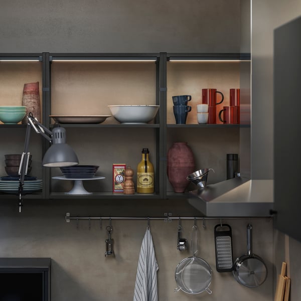 Une étagère de cuisine moderne présente divers éléments, dont un bol bleu, des tasses rouges et des bouteilles décoratives.