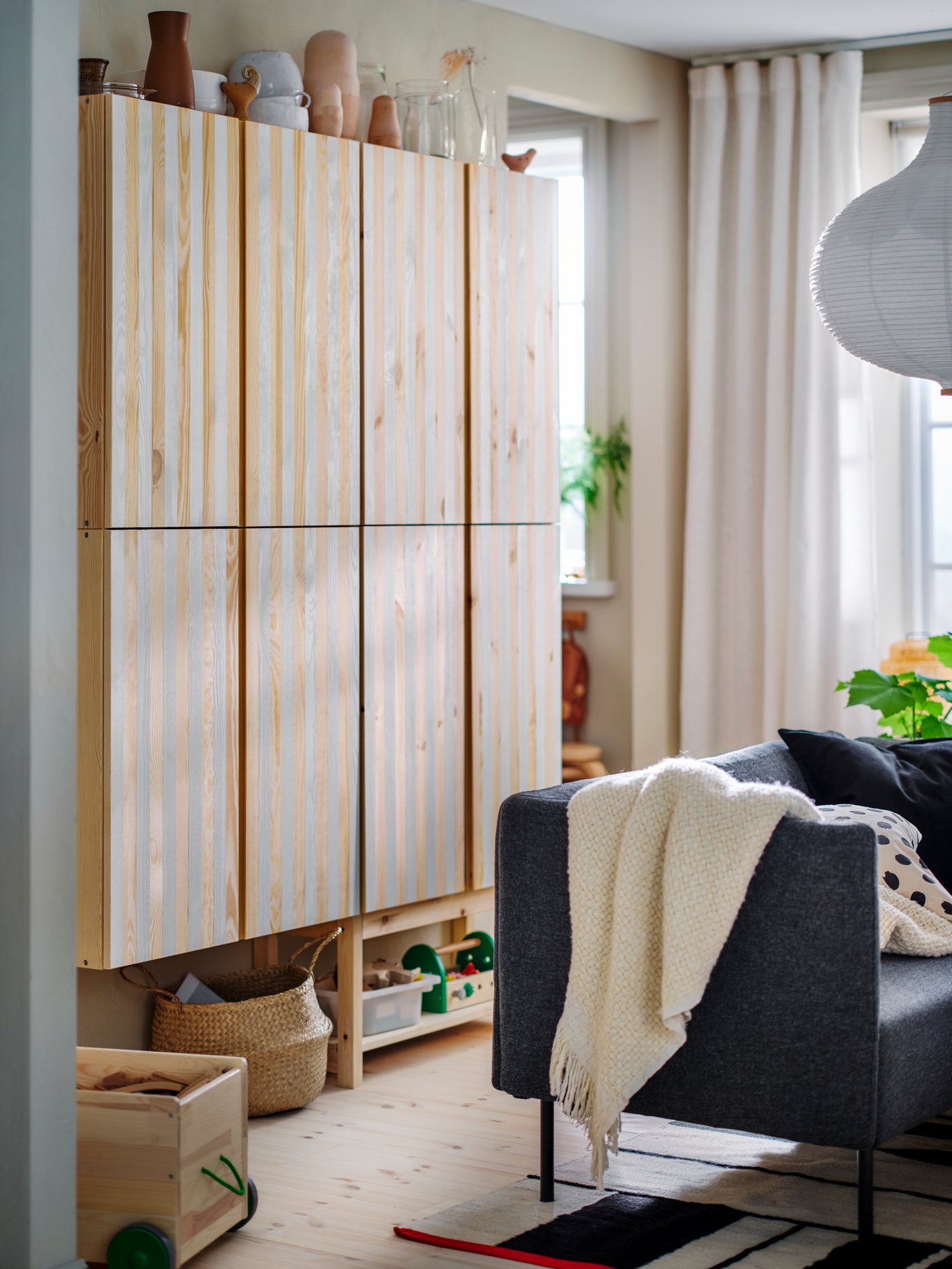 Modular LILLEHEM seating with a HUMLEMOTT throw and two extra cushions lying on it stands in front of some IVAR storage.
