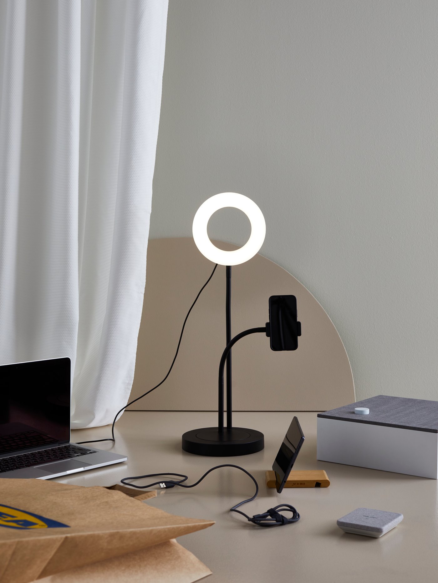 Elektronická zařízení – včetně kruhového světla LÅNESPELARE, stojanu na tablet BERGENES a Bluetooth reproduktoru ENEBY – jsou umístěna vedle sebe.