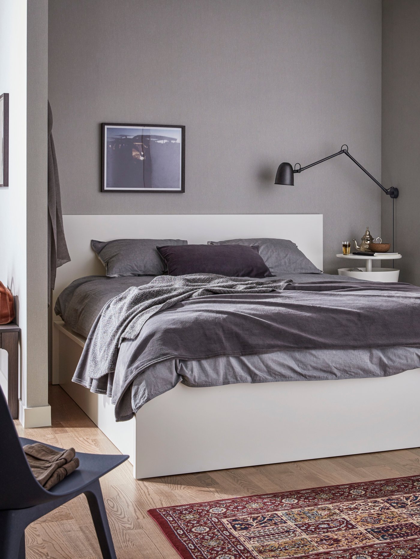 Es ist ein Schlafzimmer mit einem weissen Bettgestell mit Aufbewahrung zu sehen.