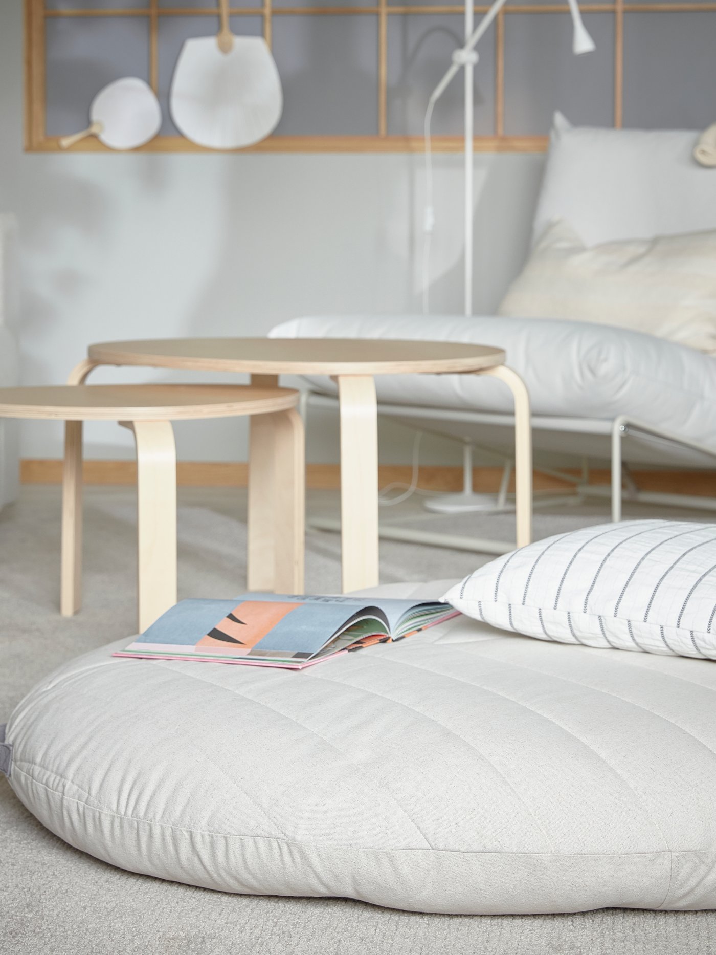 A DIHULT pouffe with handle is lying on a living room rug, and it offers a comfy and spacious seat for children.