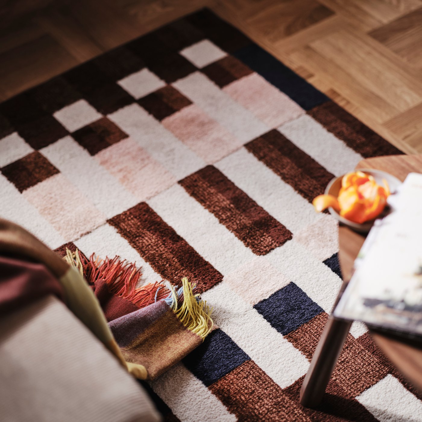 Eine Nahaufnahme eines MARKBLÅMME Teppichs mit niedrigem Flor und Karomuster sowie einer FLIKHAGTORN Decke.