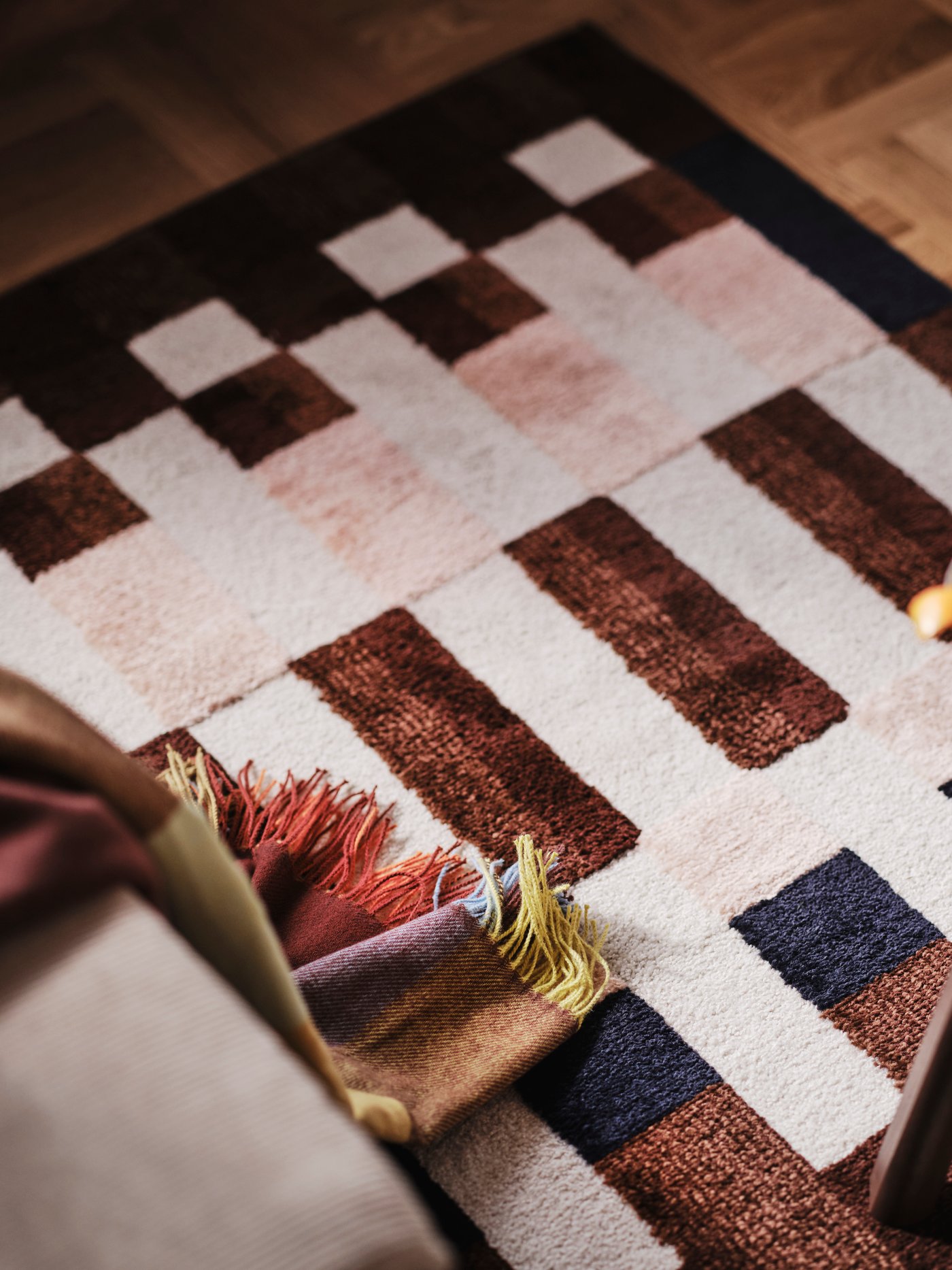 Gros plan sur un tapis aux motifs géométriques dans les tons marron, beige et noir.