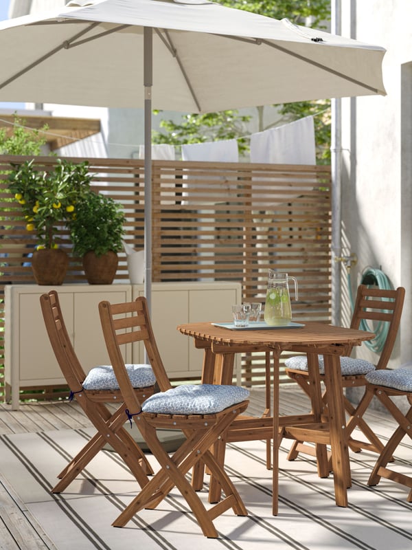 Mesa plegable de terraza ASKHOLMEN junto con cuatro sillas ASKHOLMEN con cojines de exterior.