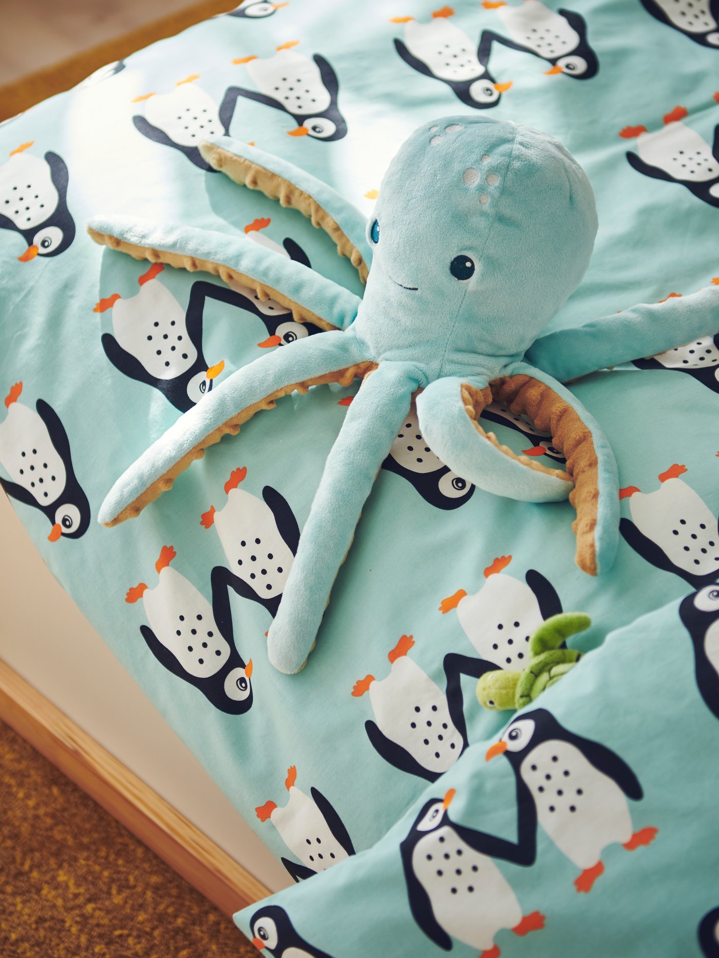 A turquoise BLÅVINGAD soft toy with LED night light, shaped like an octopus, sits on a duvet with a BLÅVINGAD duvet cover.