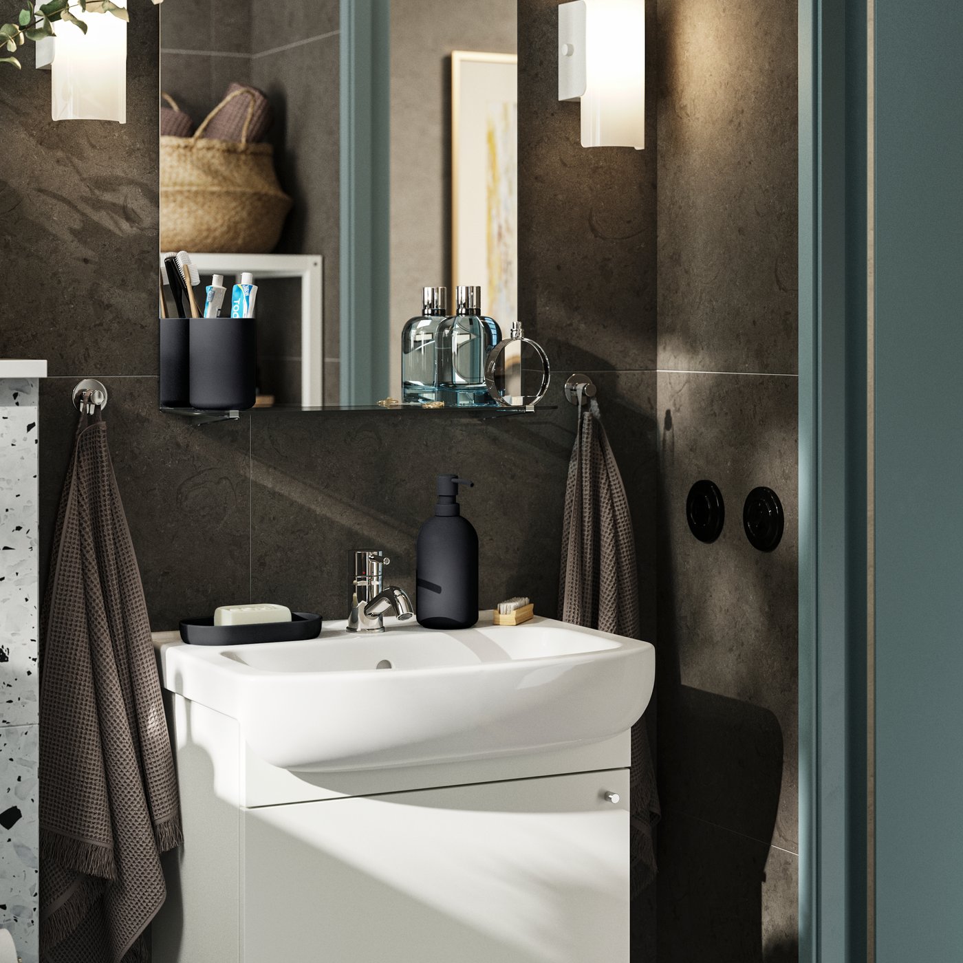 A small bathroom with dark brown walls and white furniture. A NYSJÖN cabinet with one door holds storage under the sink.
