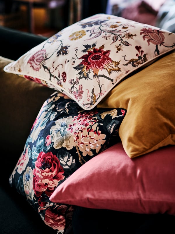 A pile of cushions made up of a LEIKNY cushion cover, a NÄSSELKLOCKA cushion cover, and two SANELA cushion covers.