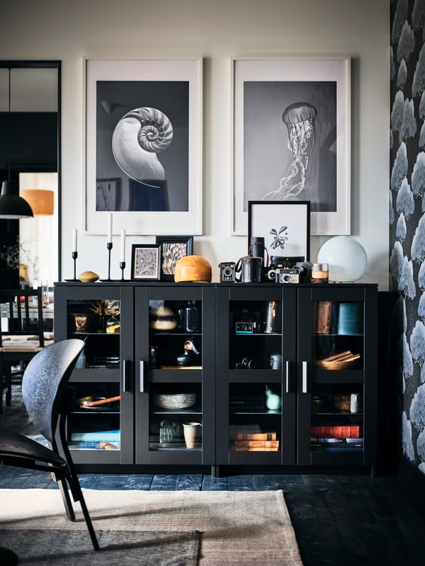 Une lampe de table FADO blanche sur un meuble BRINMES noir avec portes dans le salon