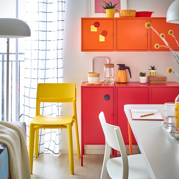 A combined dining and living room area with colorful storage and a yellow JANINGE chair.