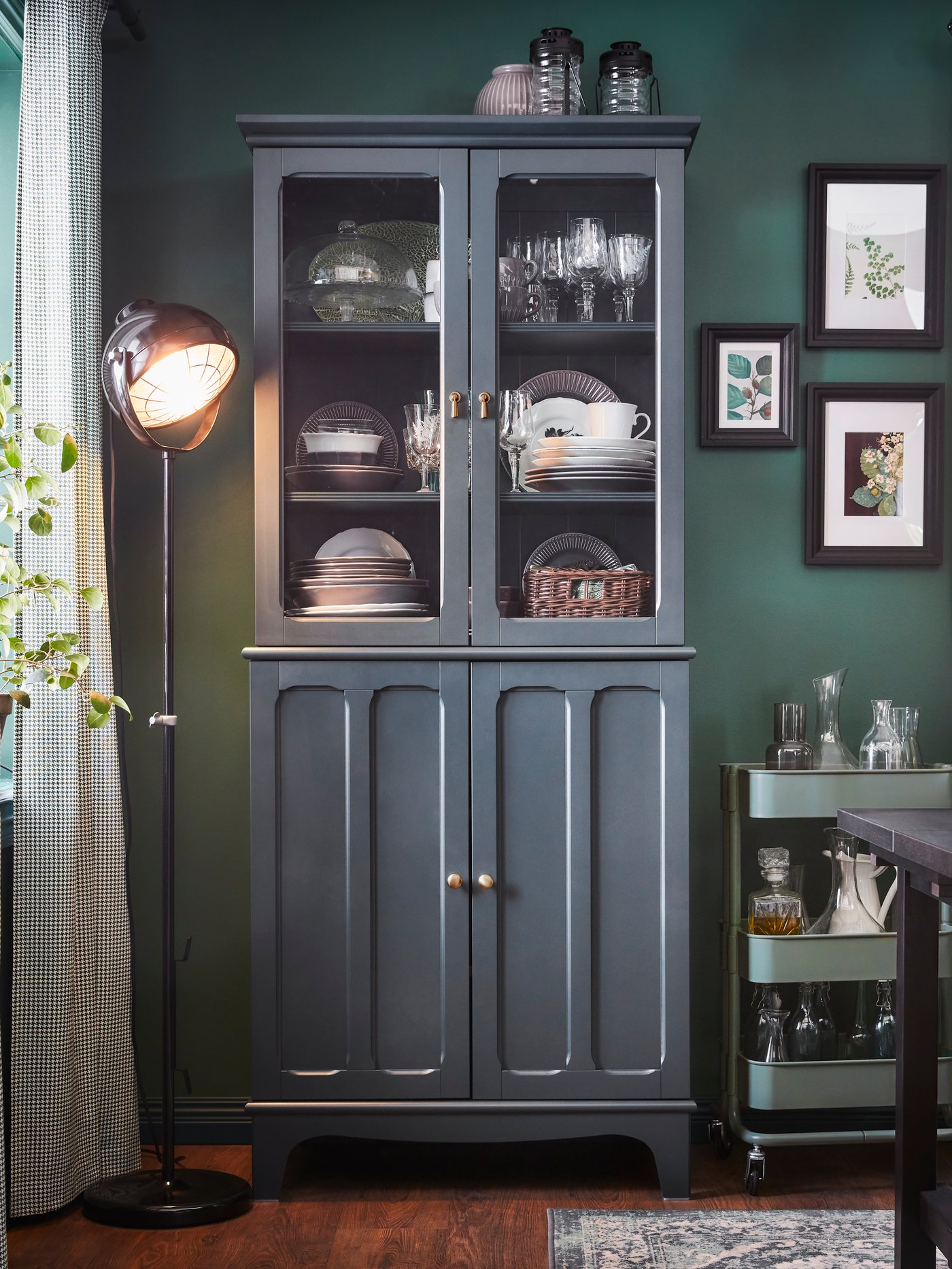 A dark blue-green LOMMARP cabinet with glass doors in the dining room