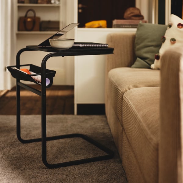 Una mesa lateral para notebook frente aun sofá IKEA.
