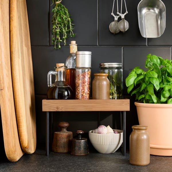 A NÅLBLECKA kitchen countertop organiser has spice jars and bottles of oil and vinegar stored on the shelf.