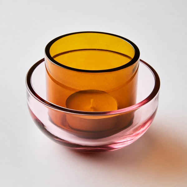 A brown TALLTITA tealight holder sits in a pink TALLTITA tealight holder. An unlit tealight is in the brown tealight holder.