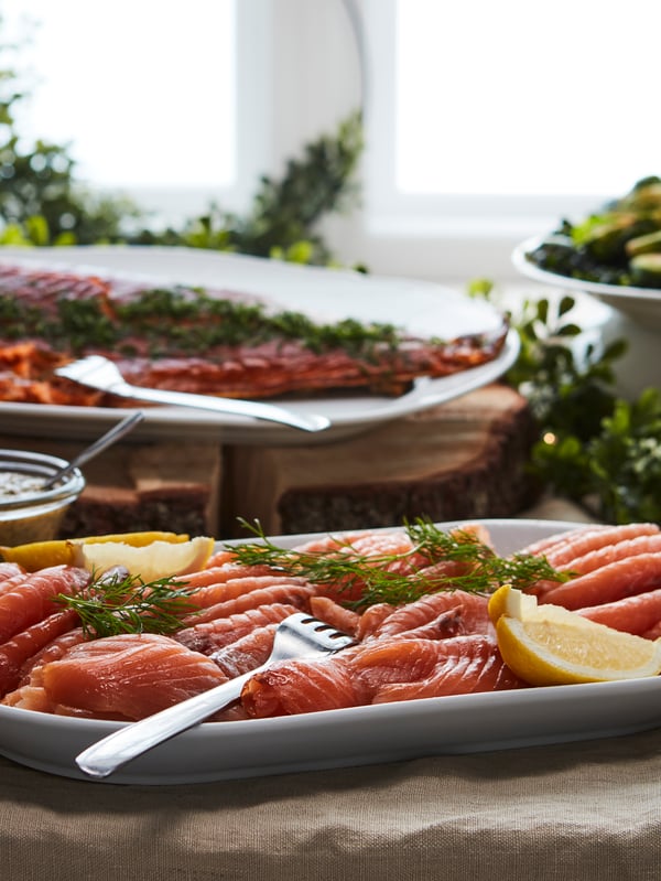 An IKEA 365+ serving plate in white holding SJÖRAPPORT cured cold smoked salmon and other food on other serving plates.