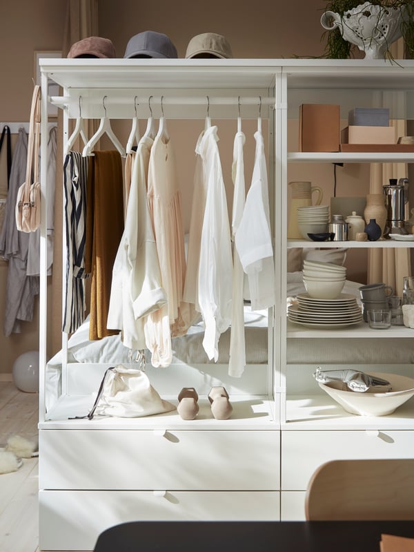 Penderie ouverte PLATSA avec tiroirs, étagères et tringle à vêtements. Vêtements sur cintres blancs et autres articles sur étagères.