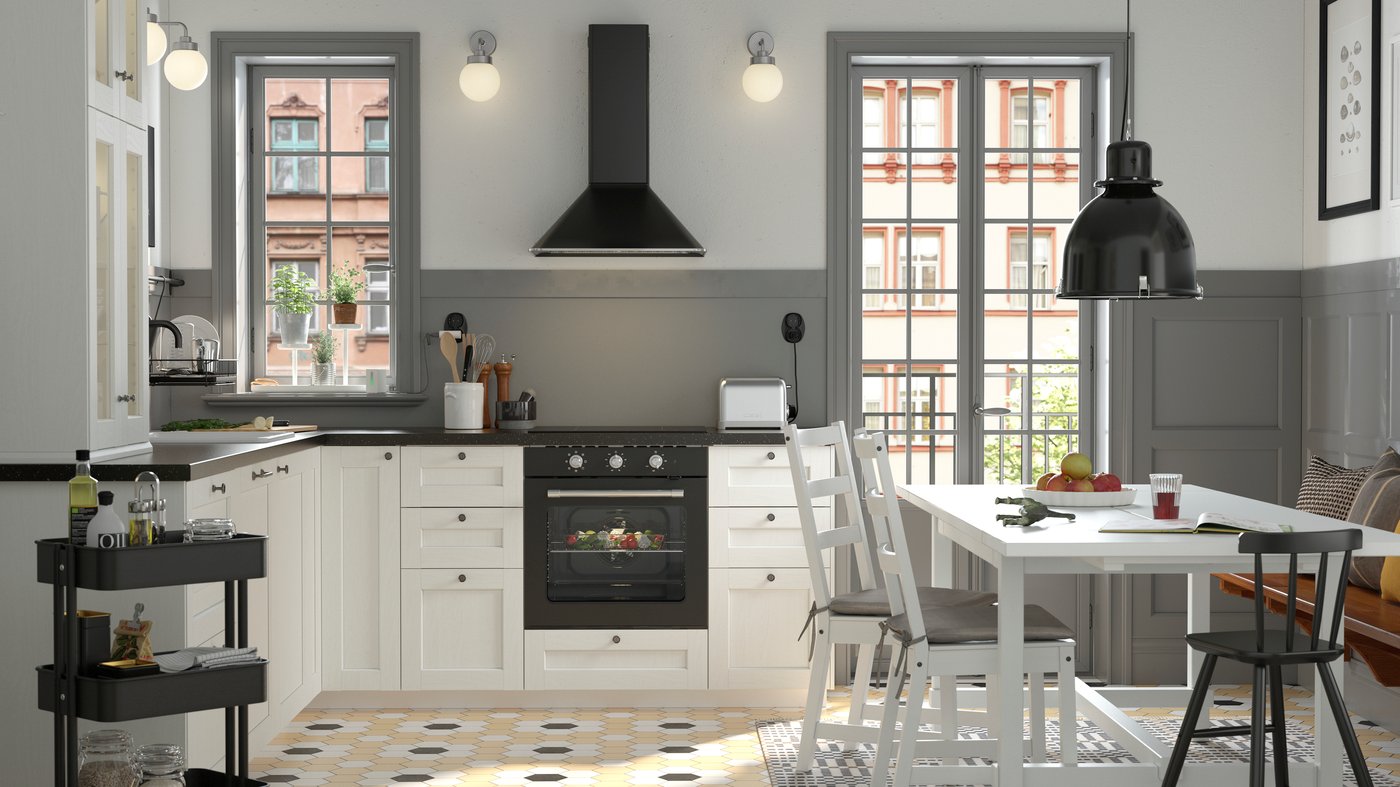 A black and white traditional-style kitchen with a white NORDVIKEN dining table surrounded by three chairs and a pine bench.