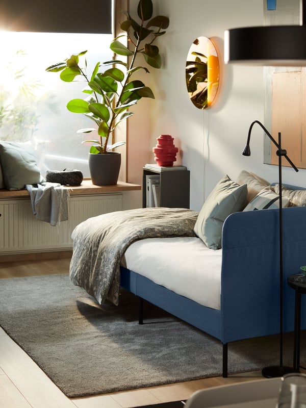Un sofá cama BLÅKULLEN en una sala pequeña convertido en cama.