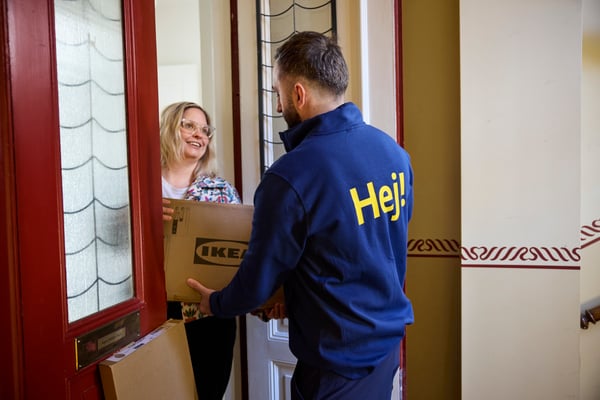 IKEA-työntekijä luovuttaa IKEA-paketteja asiakkaalle kotiovella.