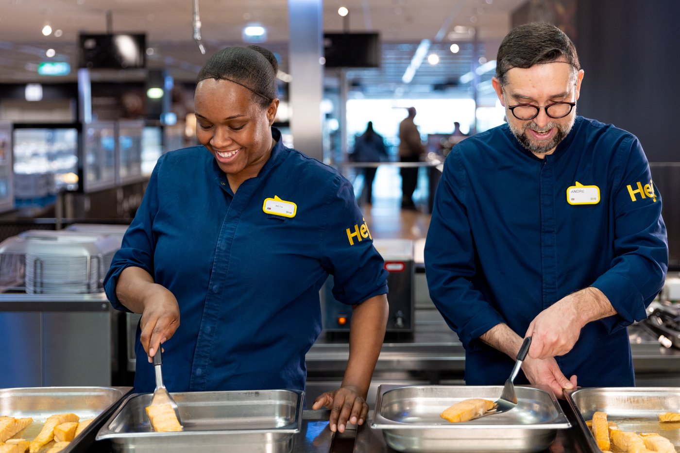 Eine Frau und ein Mann, die im IKEA Restaurant arbeiten und lachen.