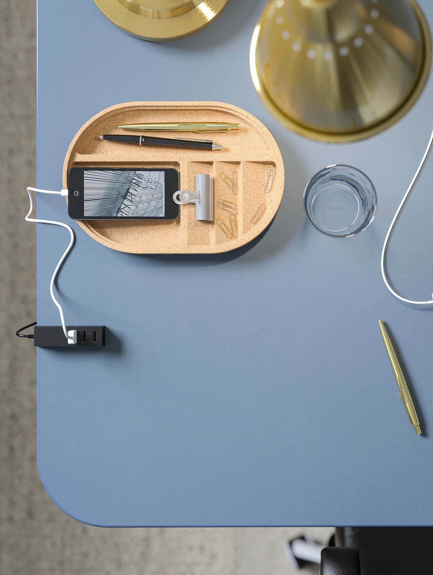 A smooth BEKANT blue linoleum table top with a glass, a phone and various office supplies like pens and pencils.