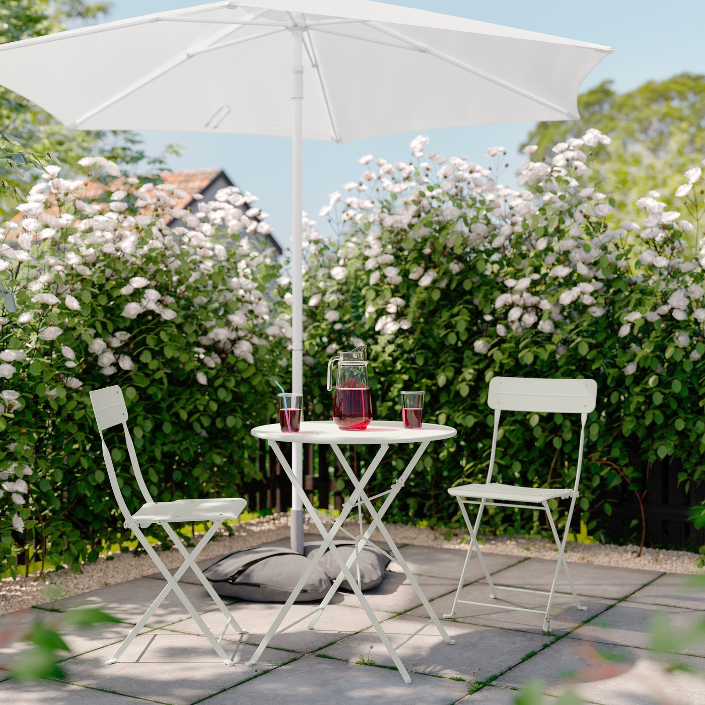 An outdoor off-white/off-white SUNDSÖ table and 2 folding chairs outside