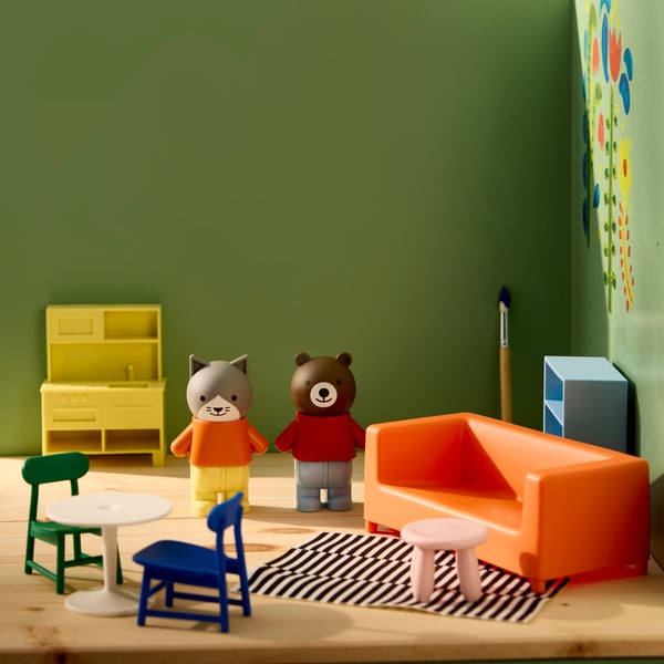 A colourful HUSET dollhouse furniture set features playful figures, a bright sofa, and a table in a vibrant room.