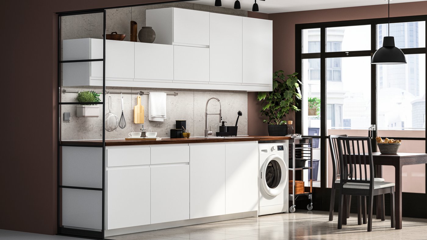A modern matt white IKEA VOXTORP kitchen with a dark worktop and EKEDALEN brown table and chairs