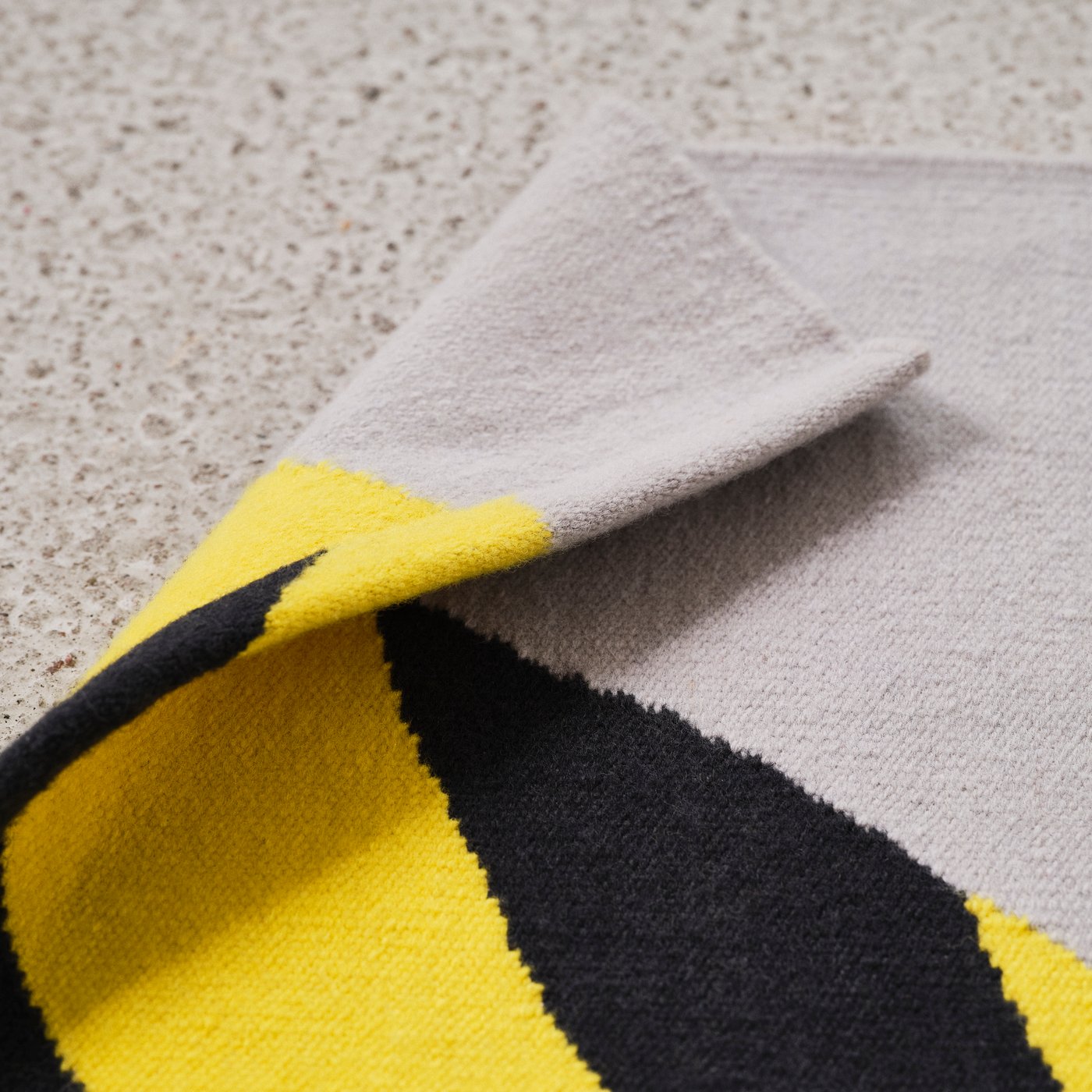 Detail mustast, kollasest ja hallist vaibast, mis on üks IKEA KONSTRUNDA kunstikollektsiooni vaipadest.