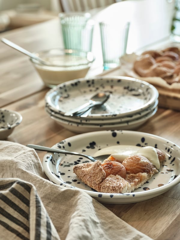 Several SILVERSIDA plates in a decorative blue pattern and one plate has a serving of fruit pie with vanilla sauce.
