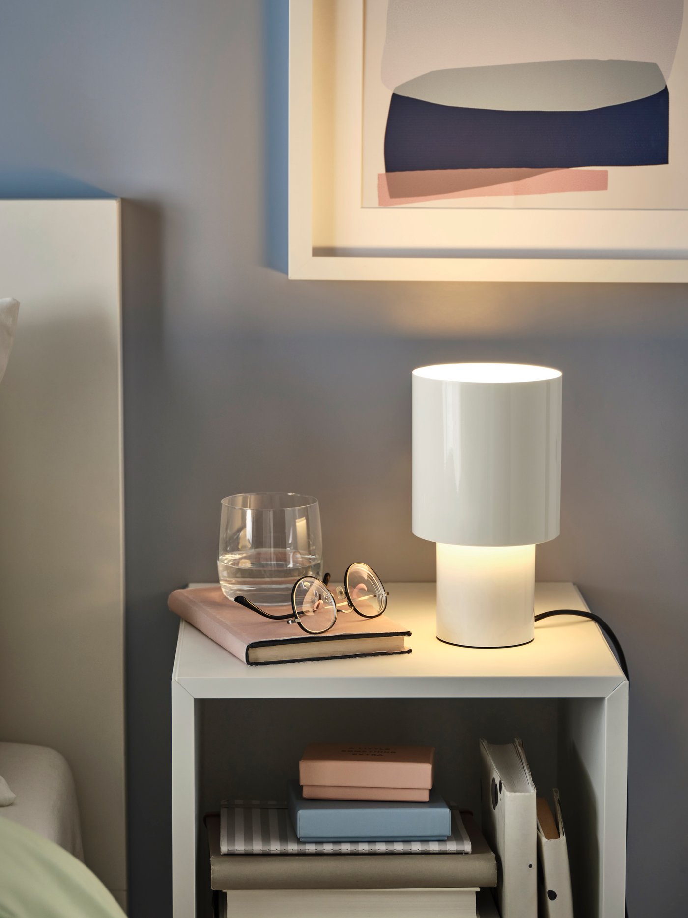 Une lampe de table SPETSBOJ blanche à intensité variable dans une chambre.