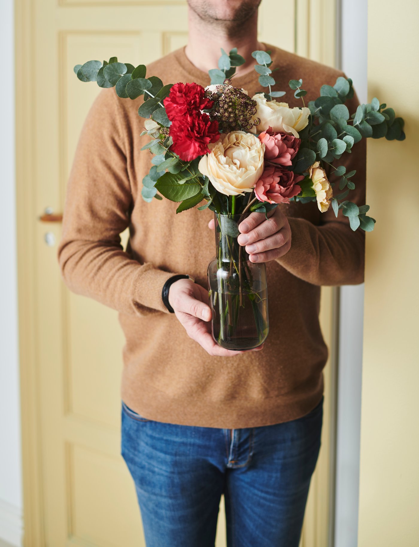 Someone is holding a light grey FÖRENLIG vase with a SMYCKA artificial bouquet.