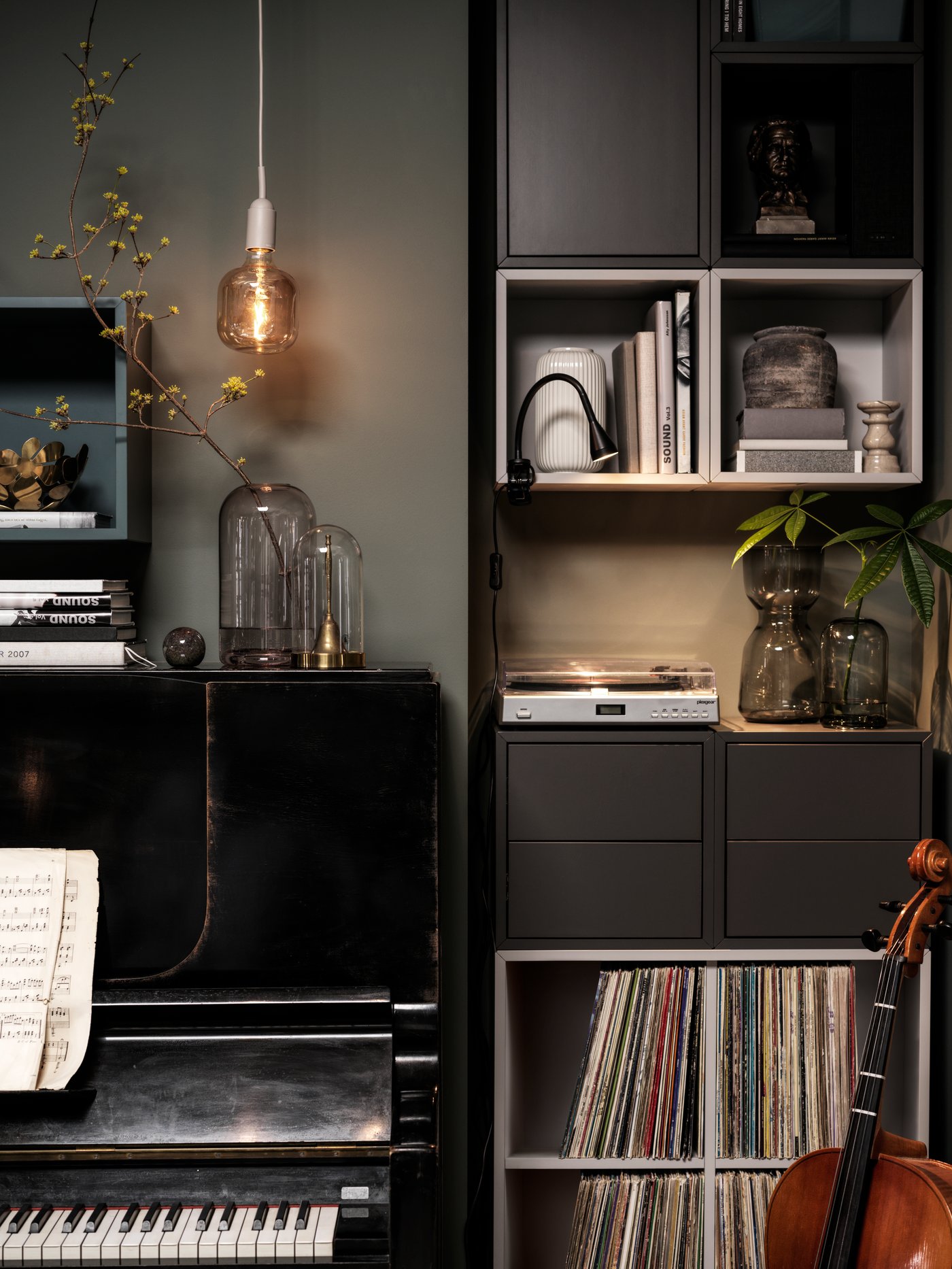 Gemütliche Musikecke mit Klavier, Regalen voller Bücher und Schallplatten, warmem Licht und Dekopflanzen.