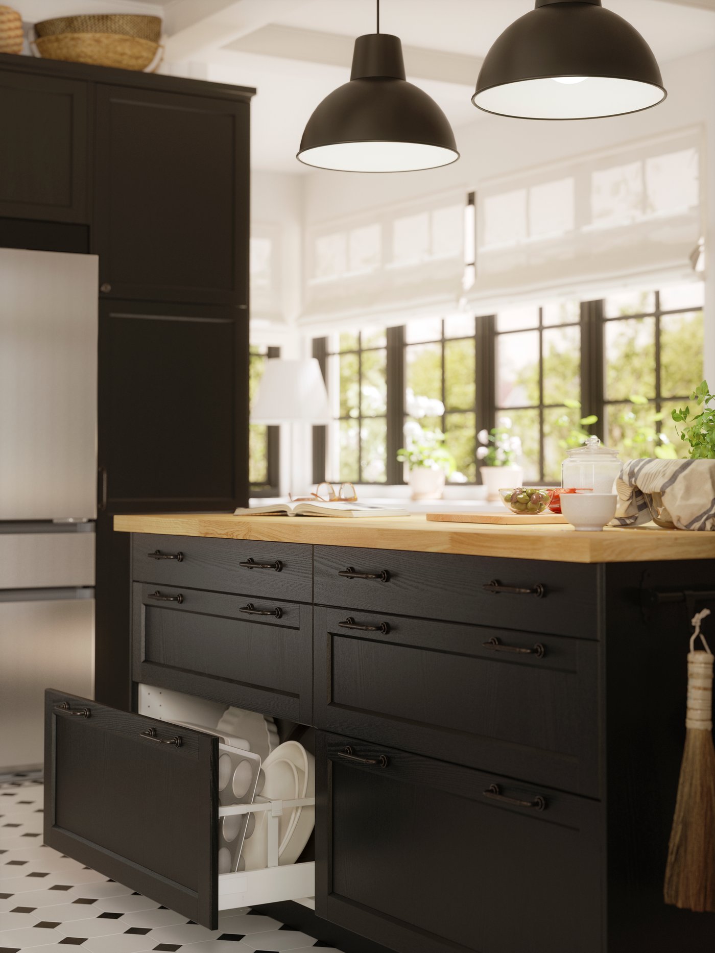 A kitchen island with LERHYTTAN black-stained fronts has a drawer that has been pulled out, showing white dishes inside.